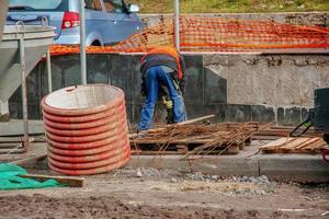 trabalhos de construção na colocação de tubos de esgoto em áreas urbanas. trabalho de trator e escavadeira. foto