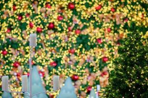 pequena árvore de natal com fundo colorido de luzes bokeh de outro grande para o festival de férias de natal. foto