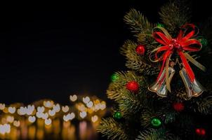 os enfeites de sino decoram na árvore de natal com fundo de luzes de bokeh de forma de amor. conceito de natal e ano novo. foto