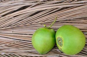 jovem fresco tailandês verde suculento e doce cocos que é fresco para o verão isolado no fundo de folhas marrons secas. foto