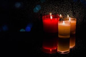 foco e velas acesas borradas colocadas ao lado da gota de chuva na janela em fundo escuro com luz bokeh. foto