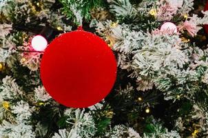 bugiganga vermelha e luzes decoram na árvore de natal que tem neve falsa. foto