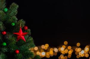 os enfeites de estrelas decoram na árvore de natal com fundo de luzes bokeh. conceito de natal e ano novo. foto