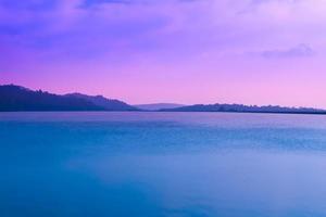 bela paisagem no lago com as montanhas e o céu, pôr do sol como pano de fundo. foto