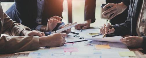 pessoas de negócios reunidas usando computador portátil, calculadora, notebook, papel gráfico do mercado de ações para planos de análise para melhorar a qualidade no próximo mês. conceito corporativo de discussão de conferência foto