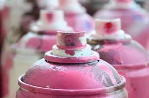 um monte de latas de aerossol sujas e usadas de tinta rosa brilhante. fotografia macro com profundidade de campo rasa. foco seletivo no bico de pulverização foto