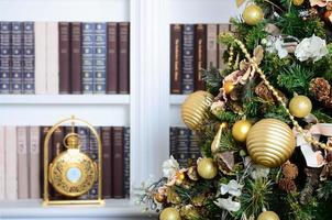 uma linda árvore de natal decorada no fundo de uma estante com muitos livros de cores diferentes e relógio dourado. imagem de fundo de natal da biblioteca foto