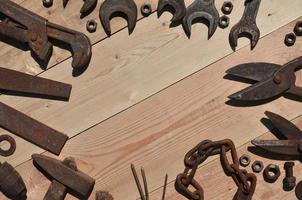 um conjunto de ferramentas velhas e enferrujadas encontra-se em uma mesa de madeira na oficina