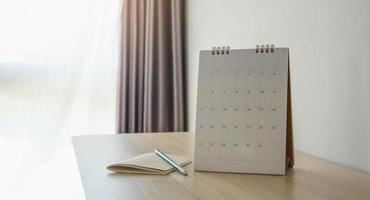 página do calendário fechar no fundo da mesa de madeira com lápis e caderno conceito de reunião de planejamento de negócios foto