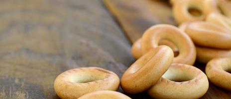 muitos bagels amarelos frescos estão na superfície da velha madeira escura. um tipo popular de produtos de farinha. uma das guloseimas tradicionais russas para o chá foto