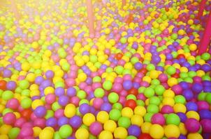 muitas bolas de plástico coloridas em uma piscina infantil em um playground. padrão de close-up foto