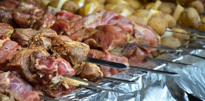 carne crua e batatas são plantadas em espetos de metal. o processo de cozinhar shish kebabs. comida de acampamento russa e ucraniana foto