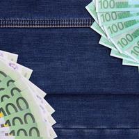 o leque de muitas notas de euro está em uma superfície de jeans escuro. imagem de fundo foto