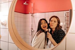 meninas muito rindo olhando no espelho. foto interna de abraçar amigos  sorrindo no banheiro 12923168 Foto de stock no Vecteezy