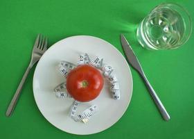 fita de tomate e centímetro em um prato, garfo e faca, um copo de água foto