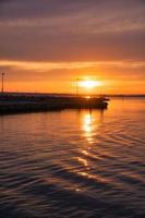 pôr do sol na suécia no porto do lago vaettern. farol ao fundo foto