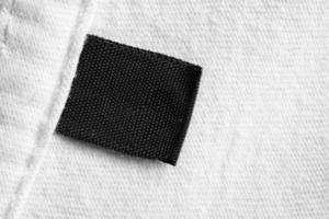 etiqueta de roupas de lavanderia em branco preta no fundo da camisa de algodão branco foto