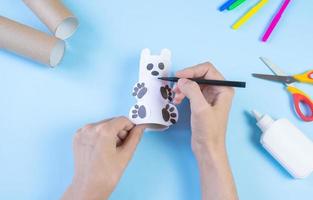 artesanato diy fácil festivo para crianças. rolo de urso de brinquedo de papel higiênico em um fundo azul. decoração criativa ecologicamente correta, reutilização, reciclagem, conceito artesanal sem desperdício mínimo foto