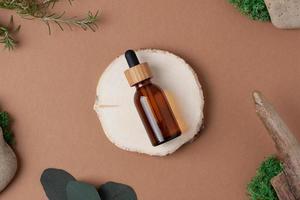 frasco cosmético com madeira e musgo em fundo natural marrom. postura plana. foto
