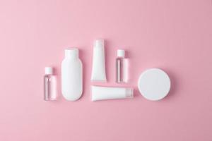 composição cosmética com produtos para cuidados com a pele em fundo rosa. postura plana, copie o espaço foto