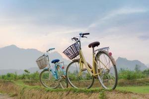 duas bicicletas ao pôr do sol com vista para a montanha em vang vieng foto