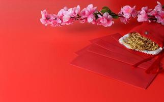 fundo de ano novo chinês - envelope vermelho, flor de ameixa e ornamento de ouro sobre fundo vermelho foto