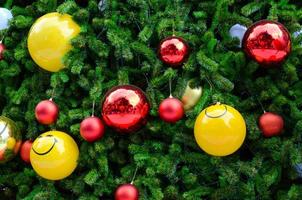 árvore de natal decora com enfeites amarelos vermelhos, dourados e sorridentes para o feriado de natal foto