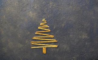 árvore de natal feita de biscoitos de canudos de pepero, em fundo de textura preta. vista de cima. foto