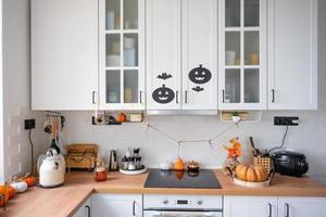 o interior da cozinha branca de estilo escandinavo é decorado com abóboras para o halloween. clima de outono, decoração de casa para o feriado foto