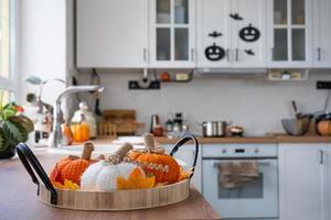 o interior da cozinha branca de estilo escandinavo é decorado com abóboras para o halloween. clima de outono, decoração de casa para o feriado foto