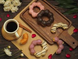 um conjunto de donuts com café preto em uma mesa de madeira foto