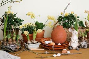 servindo da mesa de férias de páscoa com prímulas, ovos e coelhos em cor natural foto