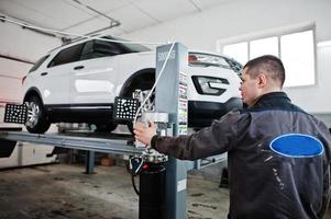 mecânico de automóveis define carro suv americano para diagnóstico e configuração de verificação de cambagem na oficina da estação de serviço.. foto