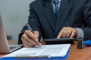 mão segurando a caneta escrevendo papelada documento de negócios investimento financeiro ou contrato de assinatura de trabalho e seguro na mesa.