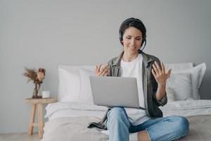 professora freelancer feminina no fone de ouvido realiza aula on-line no laptop. e-learning, trabalho distante foto