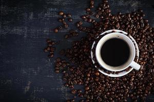 xícara de café com grãos de café em fundo escuro. caneca de café quente foto