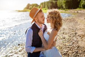 feliz jovem casal lindo em um abraço na costa do mar foto