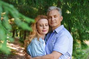 casal sênior sorridente no parque abraçando juntos e sorrindo foto