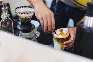 barista fazendo café com leite gelado derramando uma dose de café expresso. foto