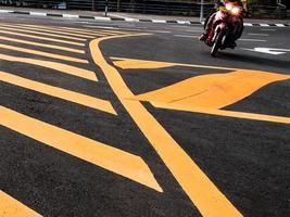 vista de ângulo baixo de um motociclista passando pelas marcações amarelas da estrada foto