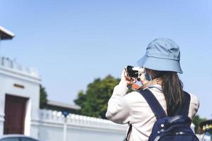 vista traseira jovem adulto asiático viajante usando câmera para viagem fotográfica. foto