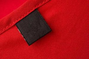 etiqueta de roupas de lavanderia preta em branco no fundo de textura de tecido vermelho foto