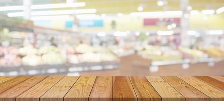 tampo da mesa de madeira com fundo desfocado da mercearia de supermercado com luz bokeh para exibição do produto foto