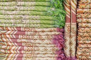 toalhas multicoloridas na prateleira no mercado, venda de toalhas de algodão, pilha de algodão colorido foto