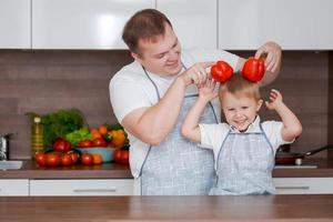 sorrindo pai e filho se divertindo segurando pimentão vermelho em forma de orelhas foto