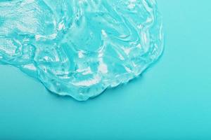 gel com ácido hialurônico na forma de uma mancha de textura brilhante em um fundo ciano. foto