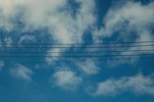 cabo, fio elétrico e linha de energia com céu azul e fundo de nuvem composto por espaço de cópia livre horizontal para fundo de tecnologia ou design de redação de anúncio foto