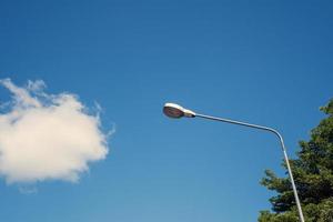 poste de lâmpada de eletricidade moderna com céu azul e nuvem como pano de fundo. luz de rua de aço ou lanterna no poste durante o dia são conceituados em industrial, tecnológico e urbanizar foto