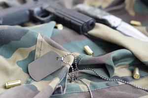 token de etiqueta de cão do exército com balas de 9 mm e pistola em tecido verde de camuflagem dobrado foto