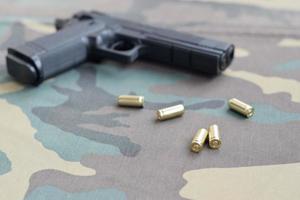 Balas e pistolas de 9 mm estão em tecido verde camuflado. um conjunto de itens de campo de tiro ou um kit de autodefesa foto